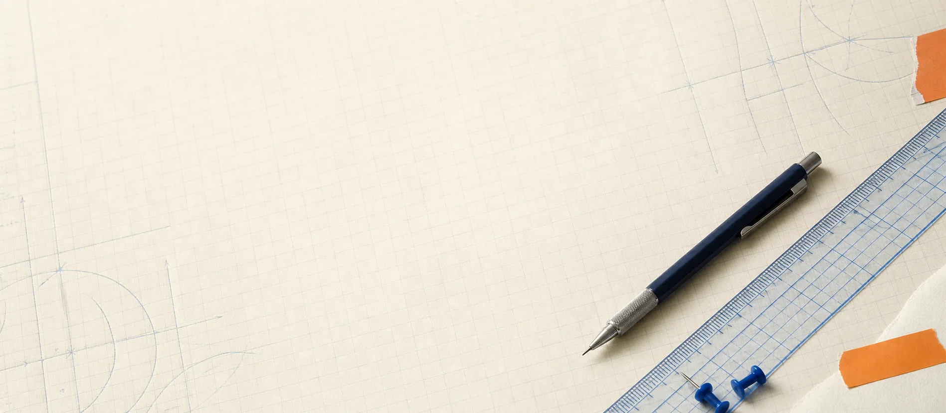 Mechanical pencil, transparent ruler, and push pins arranged on engineering paper